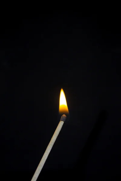 Um fósforo em chamas. Uma foto de perto, um fundo escuro — Fotografia de Stock