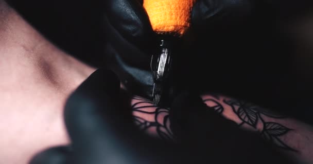 Mestre de tatuagem está trabalhando na aplicação de uma tatuagem em um salão escuro. — Vídeo de Stock
