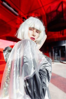 Kırmızı aynada parlak makyajlı bir sarışının portresi..