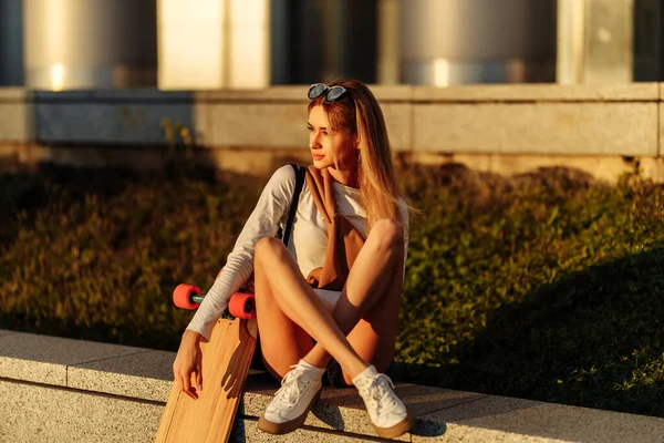 Skateboarding. Blondýna v životním stylu jezdí na longboardu v letním večeru. — Stock fotografie