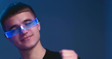 Genç bir adam parlak gözlüklerle dans ediyor..