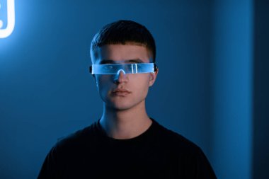 Fütürist gözlüklü neon bir odada genç bir adam..