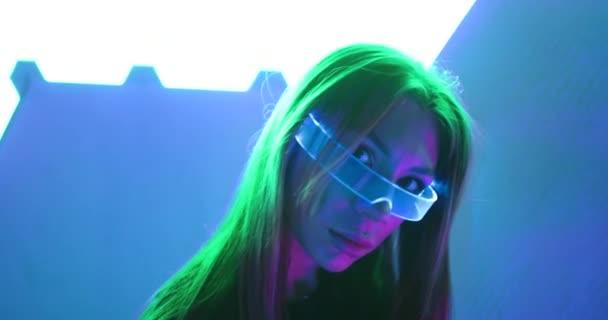 Mladá žena v neonové místnosti s neonovými brýlemi. Působí to jako obilí, hluk. — Stock video