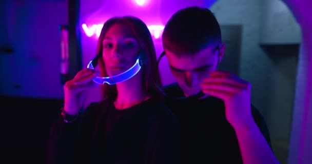 Junger Mann mit junger Frau mit futuristischer Brille im Neonlicht. Es gibt eine Wirkung von Getreide, Lärm. — Stockvideo