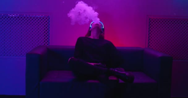Vape vapor e noir néon. Uma jovem fuma um cigarro eléctrico. Há um efeito de grão, barulho. — Vídeo de Stock