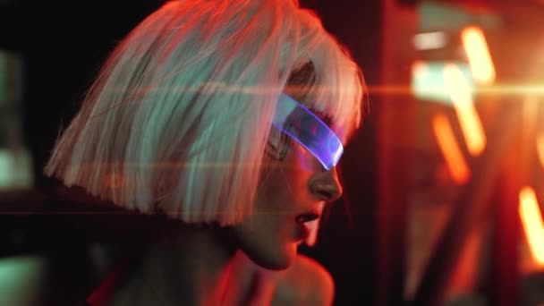 Eine Frau in neonblauer Brille wird von einem schönen Licht mit grellem Licht beleuchtet. — Stockvideo