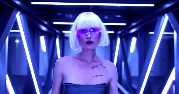 Blondynka w niebieskim neonie i futurystycznym ubraniu. Cyberpunk a moda przyszłości — Wideo stockowe