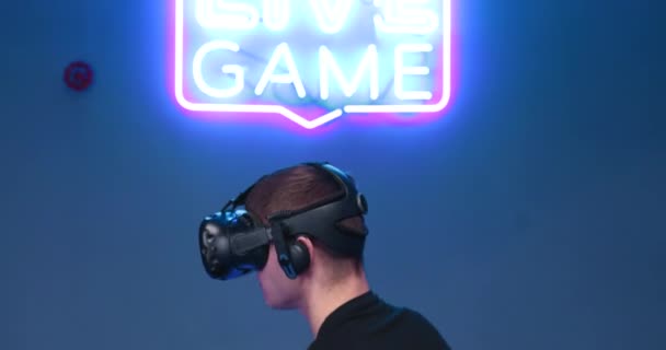 Az ember egy virtuális valóság konzolon játszik. Neonterem. — Stock videók