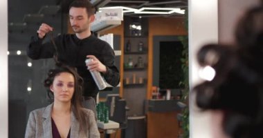 Saç spreyi sürüyorum. Usta güzel bir kadın için eski moda saç stili yapıyor..