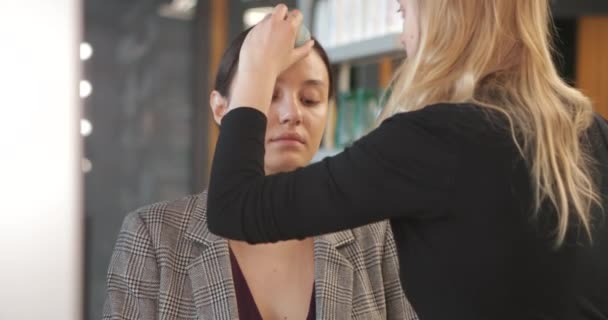 Het toepassen van make-up op een jonge vrouw in een schoonheidssalon. — Stockvideo