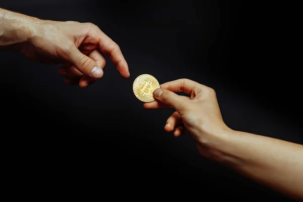 Bitcoin en la mano sobre un fondo oscuro. La mano alcanza la criptomoneda. — Foto de Stock