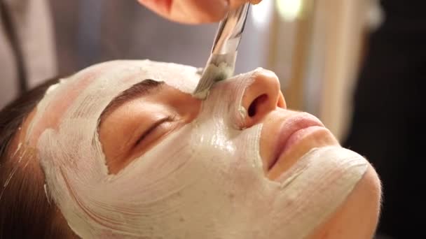 Een schoonheidsmasker op het gezicht aanbrengen met een bot. Close-up. — Stockvideo