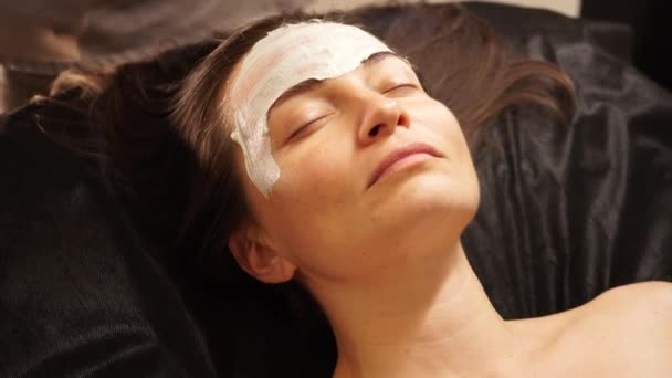 Appliquer un masque de beauté sur le visage avec un os. Gros plan. — Video