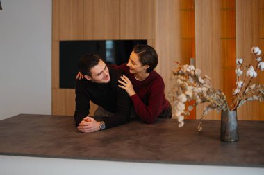 Young couple sharing a loving gaze in a stylish indoor setting.
