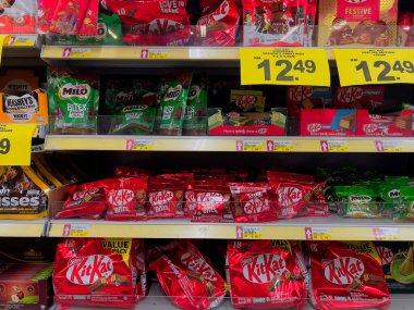 Perak, Malezya - 17 Aralık 2025: Nestle Kitkat ve Milo çikolata torbalarının çeşitliliği ve sarı perakende satış raflarında bir markette fiyat etiketleriyle sergilenen çikolatalar.