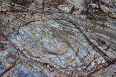 Dönen mineral desenleri ve jeolojik erozyon dokularıyla çok renkli tortul kaya oluşumunun yakın plan görüntüsü..