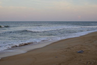 Dungun, Terengganu 'nun kumlu kıyılarında, yumuşak bir alacakaranlık gökyüzünün altında muson mevsiminde dalgaların manzarası..