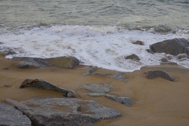 Dungun, Terengganu 'da muson mevsiminde kumlu kıyılara ve kayalara vuran dalgalı deniz dalgaları.