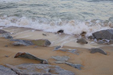 Dungun, Terengganu 'da muson mevsiminde kumlu kıyılara ve kayalara vuran dalgalı deniz dalgaları.