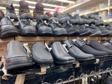 Perak, Malezya - 16 Şubat 2023: Gündelik ayakkabılar ve sağlam botlar da dahil olmak üzere çeşitli erkek ayakkabıları, bir mağaza rafında düzenli olarak satılmaktadır..