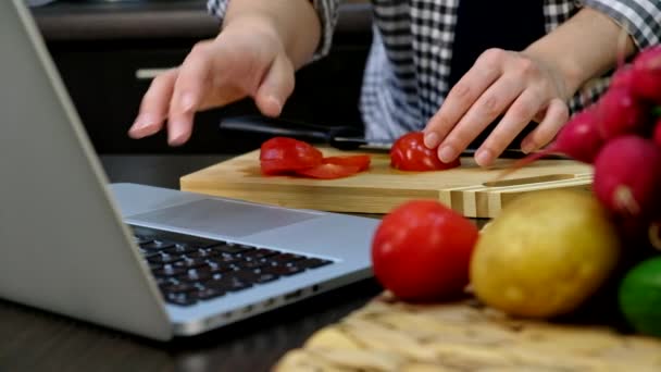 Nő főzés friss saláta vágás paradicsom figyeli recept a laptopon közeli másolás hely — Stock videók