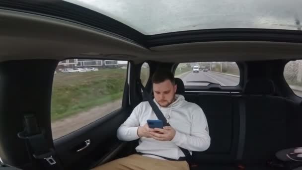 Mann sitzt hinten im Auto und schaut ins Fenster — Stockvideo