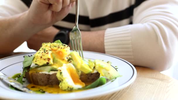 Homem comendo no café ovos sanduíche benedict abacate — Vídeo de Stock