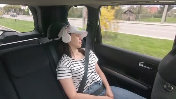 Женщина, сидящая сзади, пристегивается ремнем безопасности и слушает музыку. — стоковое видео