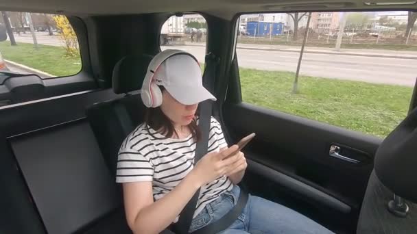 Mujer sentada en la parte trasera se sienta hebilla con cinturón de seguridad escuchando música — Vídeos de Stock