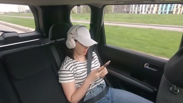 Kobieta siedzi z tyłu zapięte pasy bezpieczeństwa słuchając muzyki — Wideo stockowe