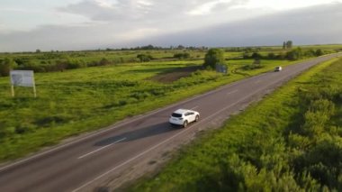 Hava görüntüsü gün batımında yarış pistinde giden arazi aracını takip ediyor.