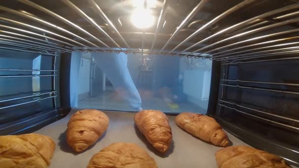 Frau holt Croissants aus dem Ofen — Stockvideo