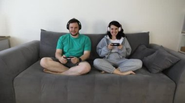 Çift kanepede oturup video oyunu oynuyor.
