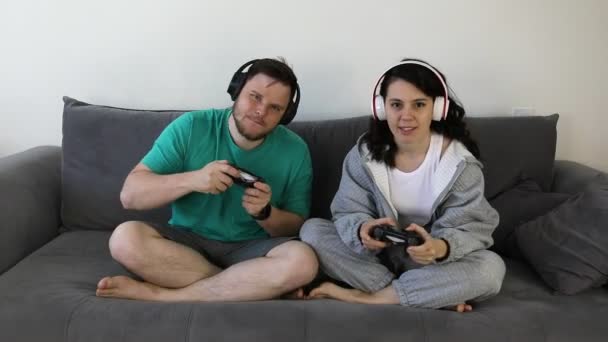 Pasangan bersama-sama bermain video game duduk di sofa — Stok Video