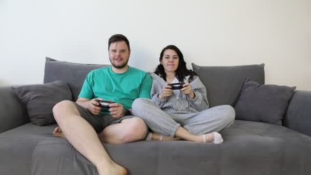 Пара разом грає у відеоігри, сидячи на дивані — стокове відео