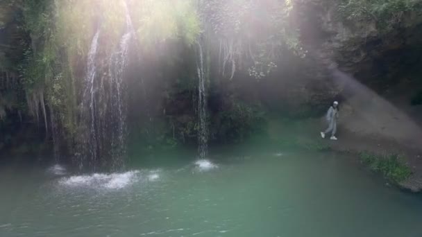 Woman hiker traveler looking at beautiful waterfall with blue lake — Stock Video