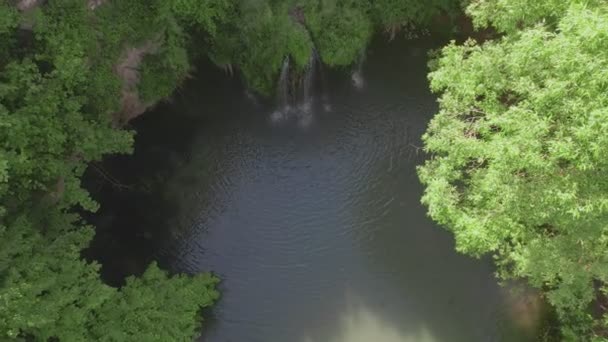 Blick von oben auf kleinen Wasserfall mit blauem See — Stockvideo