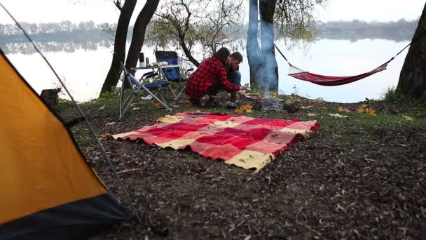 Casal descansando no outono acampamento local cozinhar no fogo — Vídeo de Stock
