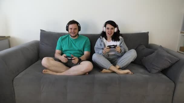 Pasangan bersama-sama bermain video game duduk di sofa — Stok Video