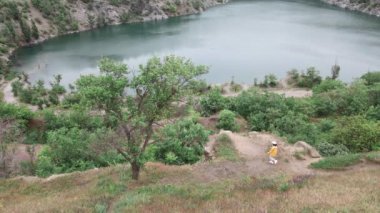 Kadın yürüyüşçü, eski su basmış maden manzarasını seyrediyor.