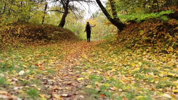Uśmiechnięta szczęśliwa kobieta spacerująca ścieżką w jesiennym lesie — Wideo stockowe
