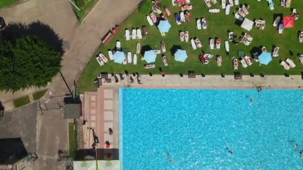 Вид зверху на людей, що купаються на шезлонгах, які плавають у громадському міському басейні — стокове відео