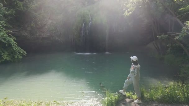 Жінка мандрівник, дивлячись на красивий водоспад з блакитним озером — стокове відео