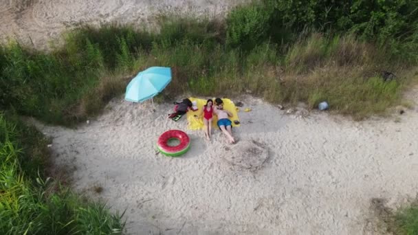 Paar sonnt sich am Sandstrand des Sees — Stockvideo