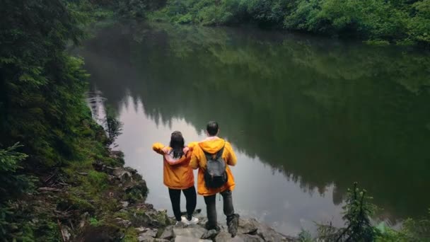 Pareja de excursionistas en la orilla del lago rocoso mirando la belleza de la naturaleza — Vídeos de Stock