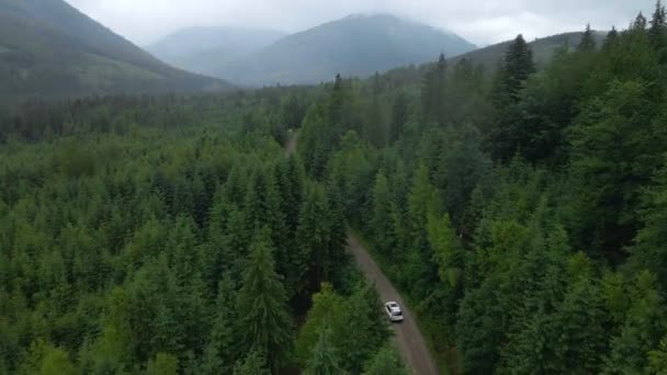 Widok z lotu ptaka SUV samochód poruszający się drogą w górach zachmurzenie mgliste deszczowa pogoda — Wideo stockowe