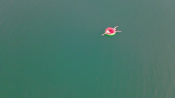 Górny widok z góry kobieta pływanie z arbuzem pływanie koło w niebieskiej wodzie — Wideo stockowe