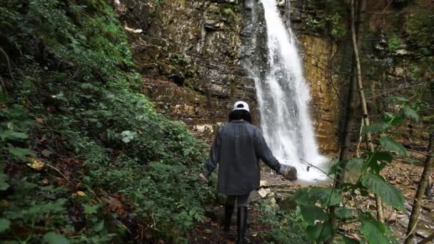 Mujer excursionista caminando a gran cascada en las montañas — Vídeos de Stock