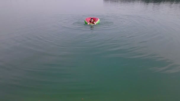 Overhead top view of woman swimming with watermelon swimming circle in blue water — Stock Video