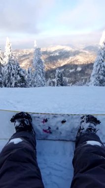 Dağların tepesinde gün batımını izleyen snowboardcu.